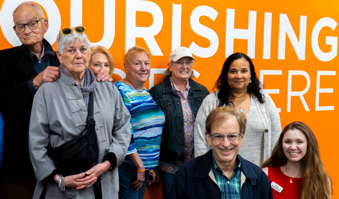 staff posing infront of the Nourishing Tomorrow Society back wall logo