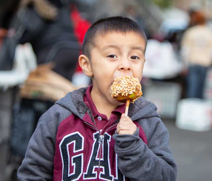 young boy eating a candied apple